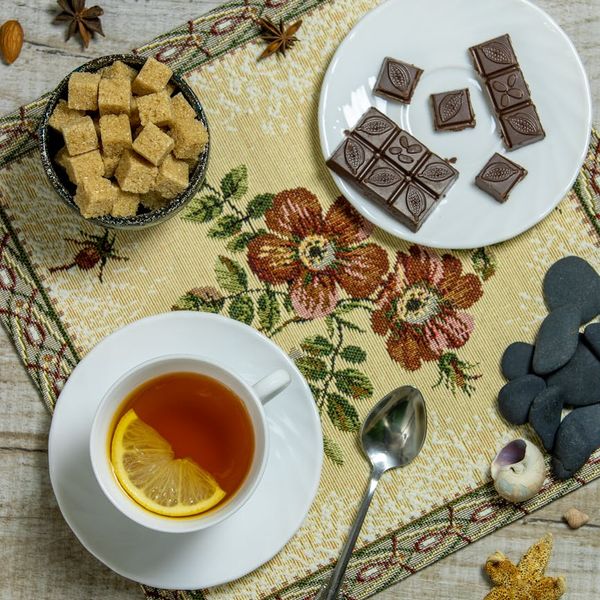A neatly arranged yoga mat, a candle, and a cup of herbal tea.