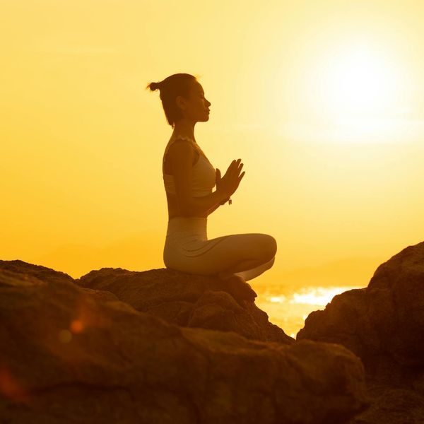 Silhouette of a person in a yoga balance pose against a sunset.
